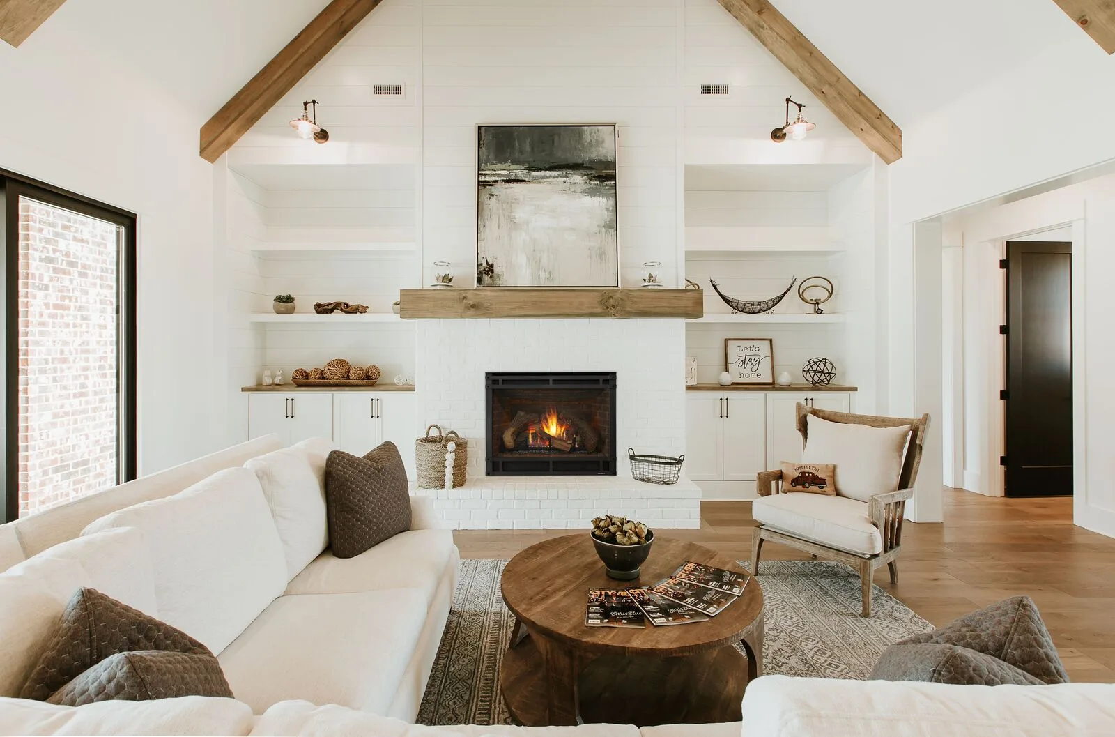 A Heat & Glo 8000CL gas fireplace burning in a white built-in wall under timber beams (manufacturer lifestyle photo)