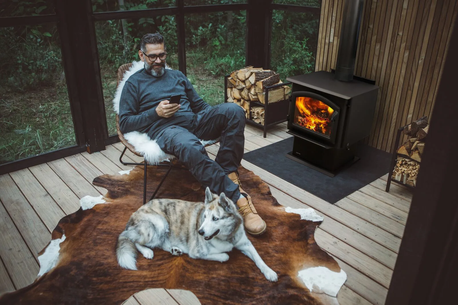 A man and his husky on a screened porch beside a black Quadra-Fire 31M wood stove (manufacturer lifestyle photo)